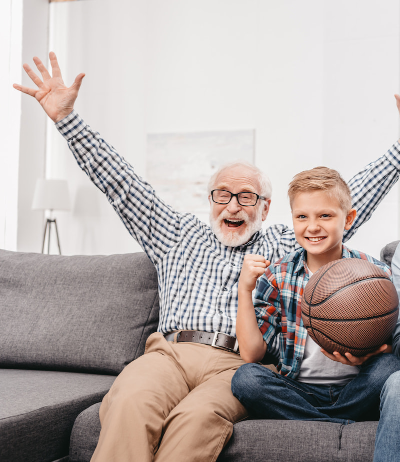 Pegasus Senior Living | Grandpa and his grandson watching basketball on the sofa together