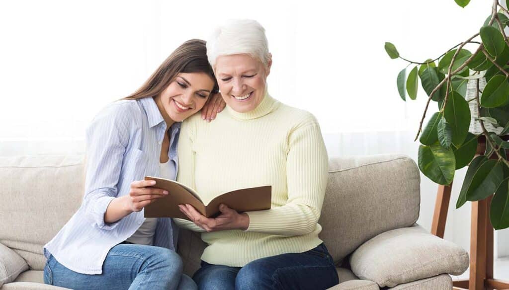 Pegasus Landing of Overland Park | Senior woman smiling reading a book with her daughter