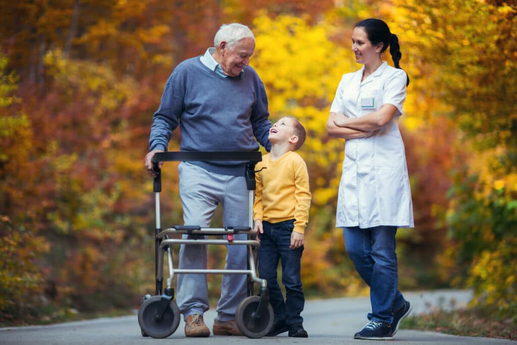 Pegasus Landing of Overland Park | Senior man and his grandson walking outside with a caregiver