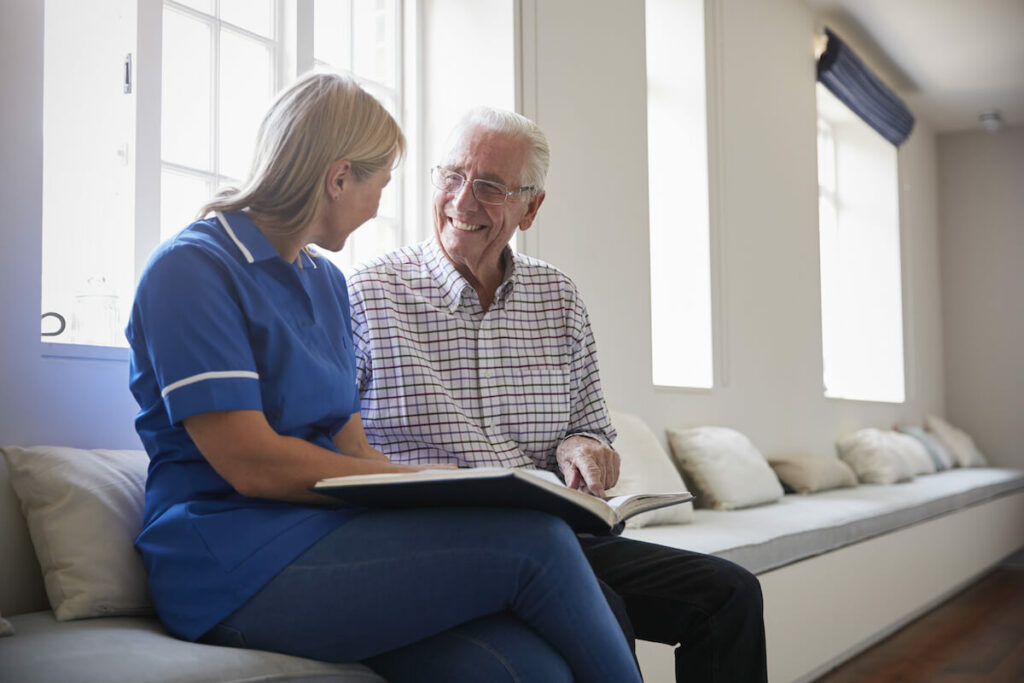 The Courtyards at Mountain View | Senior and caregiver sitting on bench inside