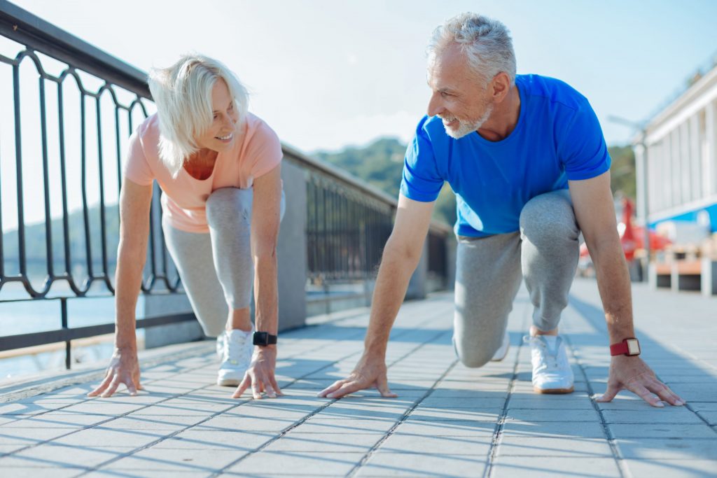 The Courtyards at Mountain View | Two seniors lunging, preparing for a foot race