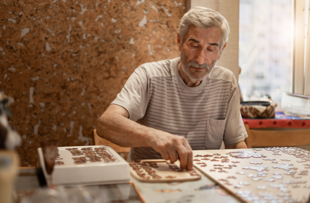 The Legacy at Crystal Falls in Leander | Senior man doing a jigsaw puzzle