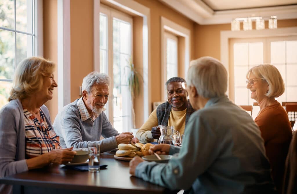 The Legacy At Falcon Point | A group of seniors sitting around a table, eating and enjoying afternoon tea while smiling and chatting with each other