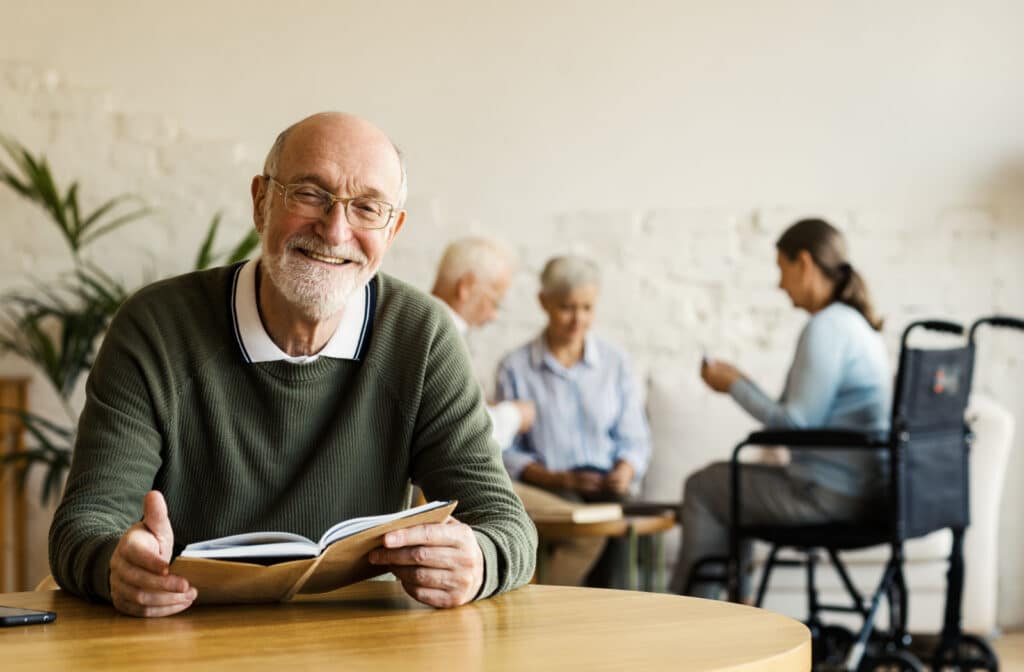 The Legacy At Falcon Point | Happy Senior Sitting At Table In Common Area