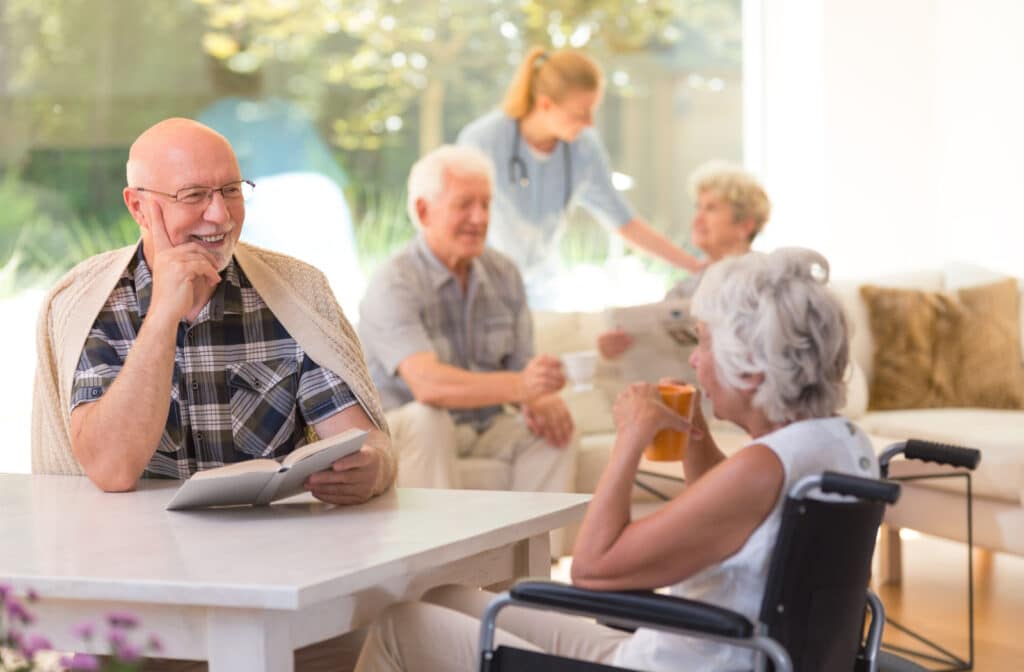 The Legacy At Falcon Point | A senior man sitting at a table holding a book and engaged in conversation with a senior woman