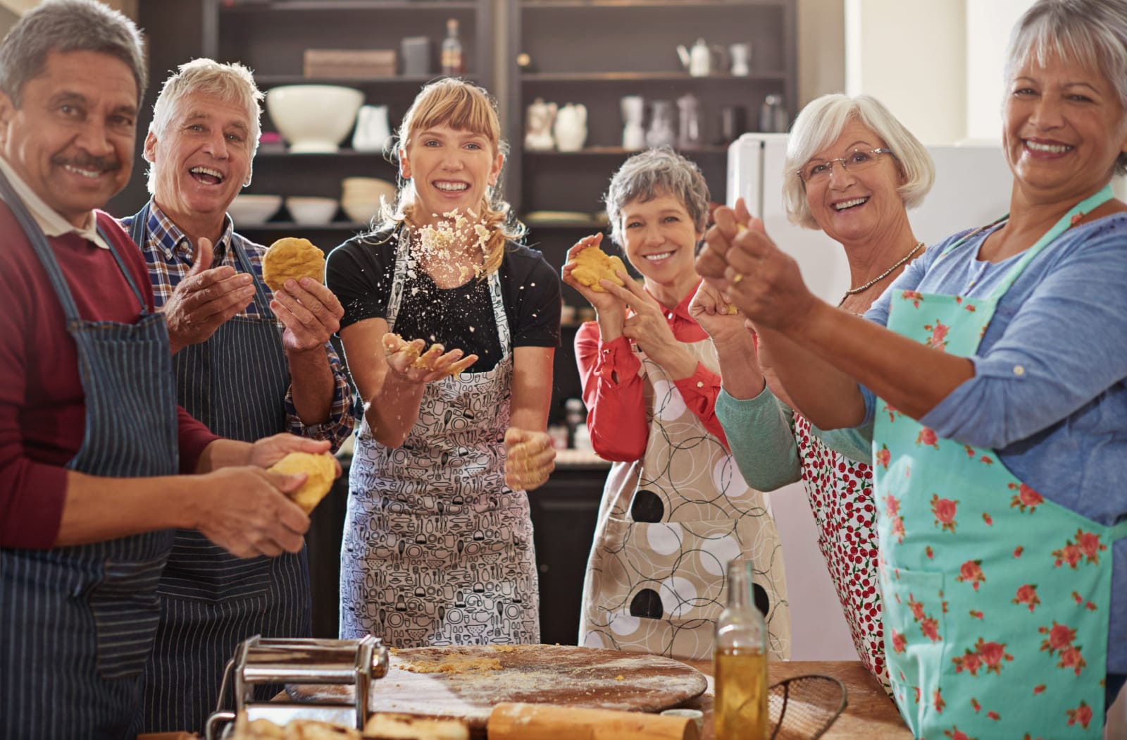 The Legacy At Falcon Point | A group of older adults in a baking class with their instructor, each holding dough, smiling and looking directly at the camera