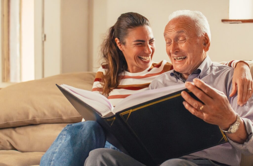 The Legacy At Falcon Point | An older adult man and his daughter smiling while looking at a photo album together.