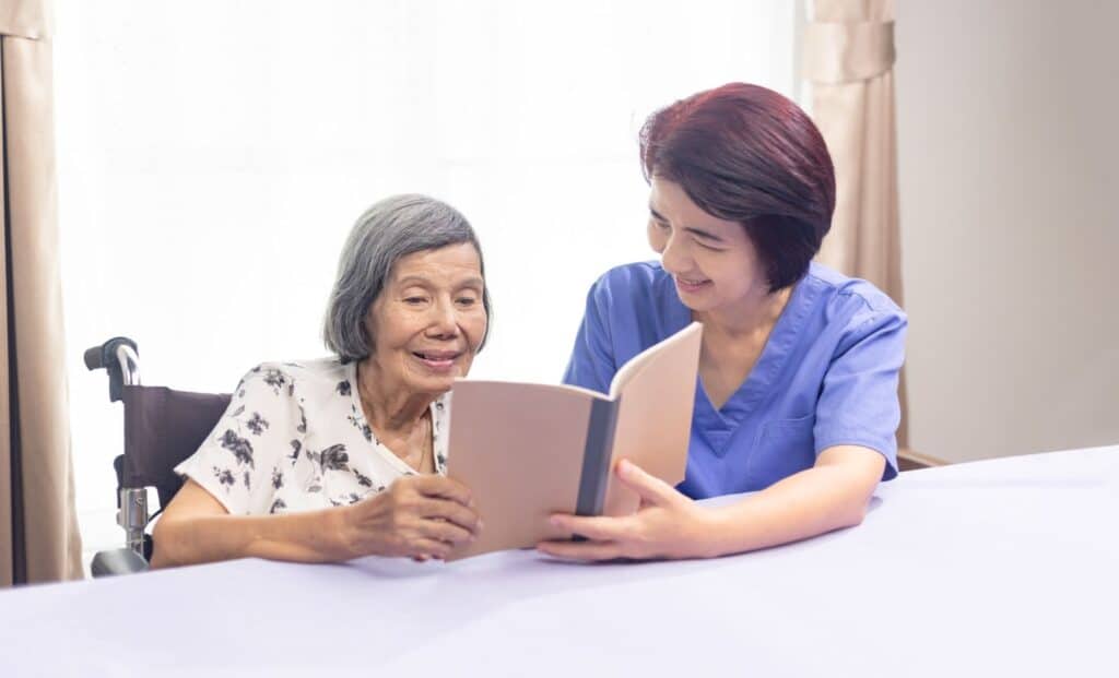 The Legacy At Falcon Point |  A woman is reading with her memory care professional to help strengthen her memory.