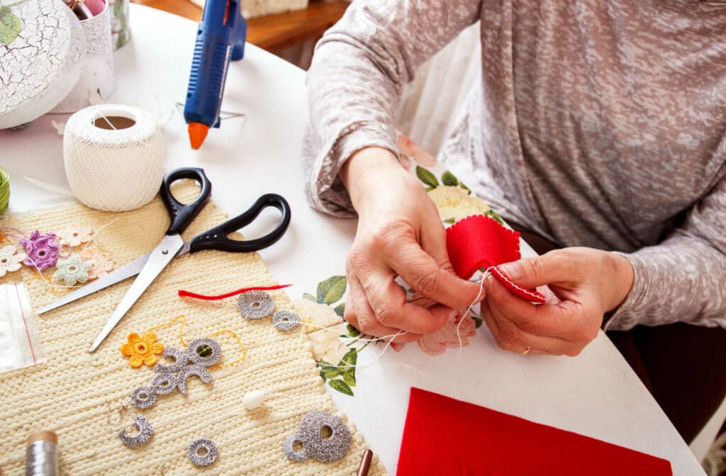 The Legacy at South Plains | A senior woman sewing a heart out of fabric to make a beautiful piece of art.