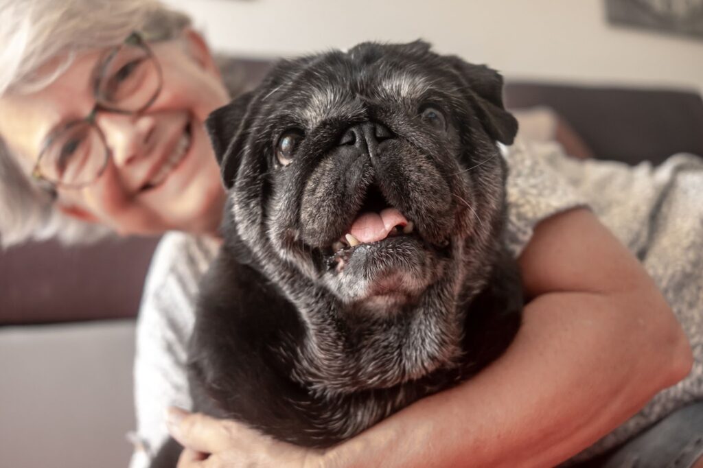 The Legacy At South Plains | An elderly woman smiles with her arm around a black dog.