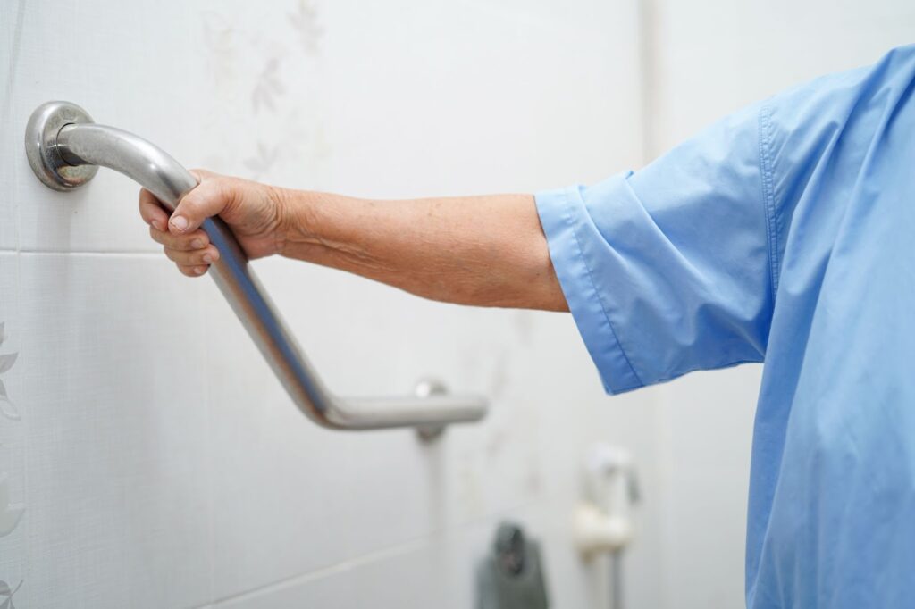 The Legacy At South Plains | An elderly person holds a grab bar in the bathroom for support.