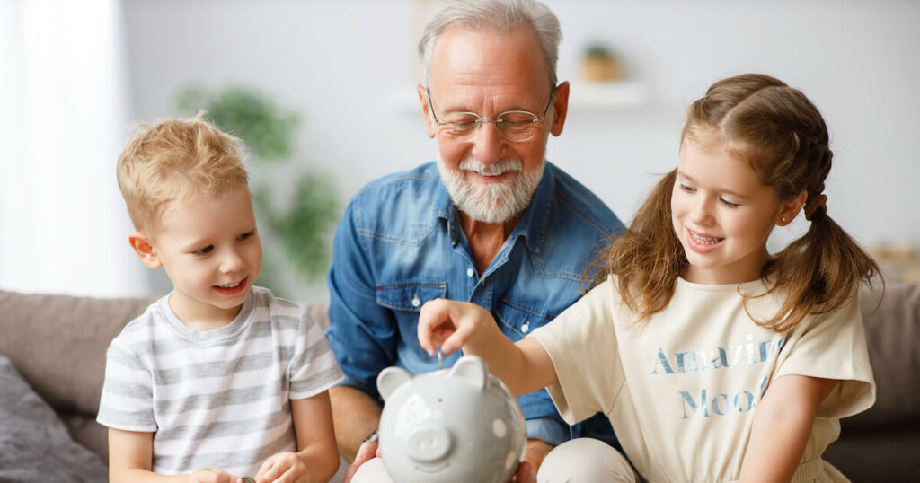 Pegasus Senior Living | Senior and his grand chi;den putting coins into a piggy bank