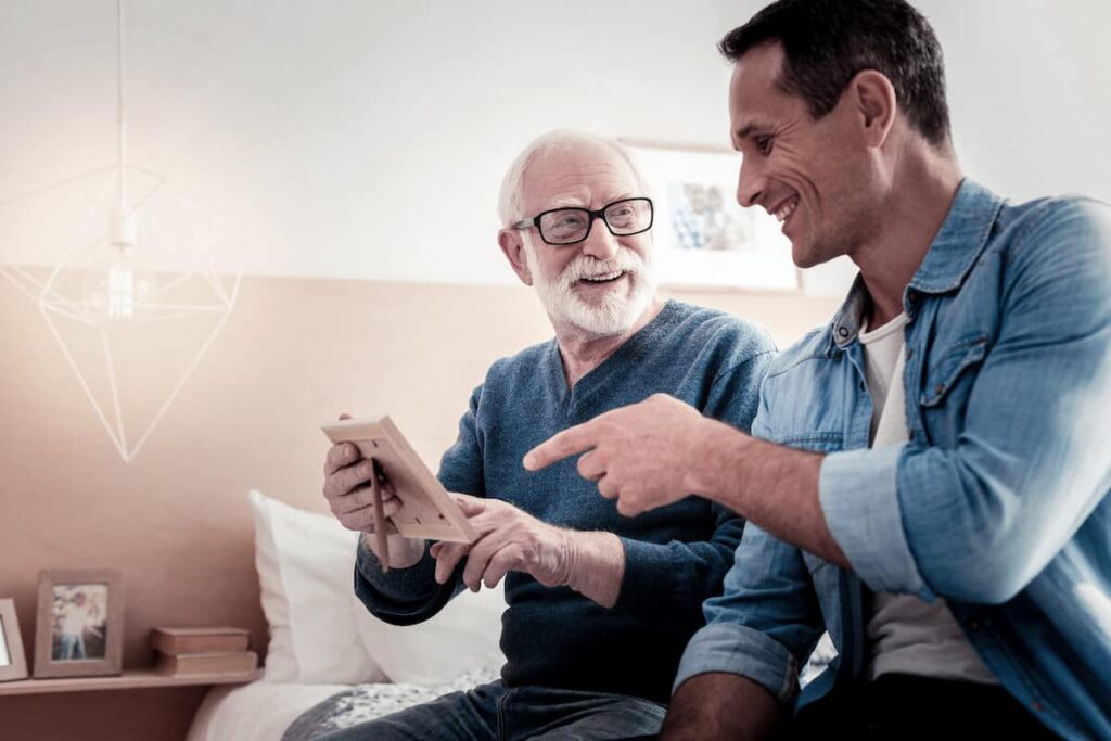 The Rivers at Puyallup | Senior man and his son looking at a picture ina frame while sitting on a bed